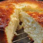 Close-up of a fluffy carnivore cake with a golden crust and a thick slice cut out.